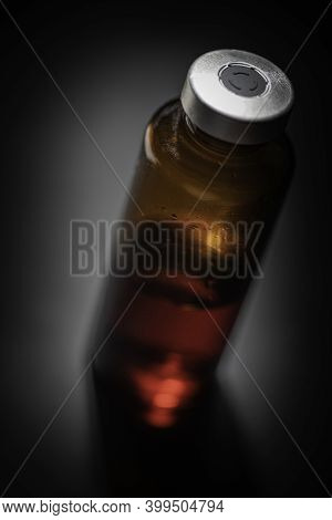A Macro Shot With Selective Focus Of An Amber Color Vaccine Injection Bottle Set On Plain Black Back
