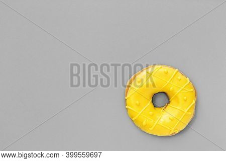 One Tasty Fresh Donut With Illuminating Yellow Glaze On Plain Gray Background. Top View Minimal Flat