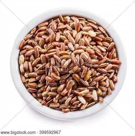 Brown rice - whole grain rice with outer hull or husk in ceramic bowl on white background. File contains clipping path.