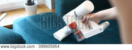 Close-up Of Womans Hand Cleaning Sofa With Small Electrical Compact Vacuum Cleaner. Stylish Seagreen
