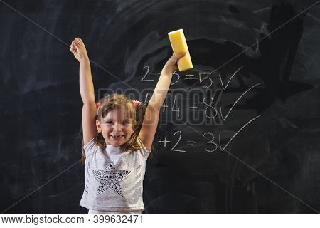 Schoolgirl Standing In Front Of A Blackboard, Happy After Solving Math Equations And Practising Summ