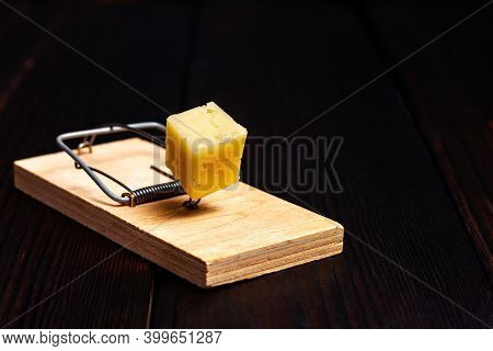 Wooden Mousetrap With A Piece Of Yellow Cheese On A Dark Wooden Background. Rodent Trap. Catch The M