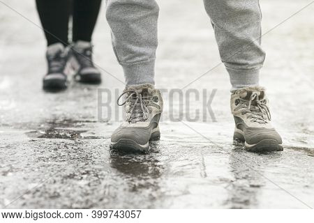 Pedestrians Glide Along The Icy Sidewalk. Winter Ice On Footpaths.