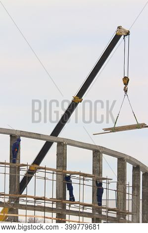Builders Working On A Construction Site, Against The Background Of An Industrial Landscape, Metal An