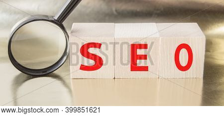 Seo Search Engine Optimization Text Wooden Cubes And Magnifying Glass On A Golden Background. Idea, 