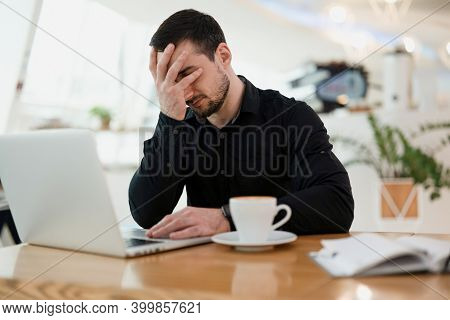 Freelancer Man Facepalming. Remote Work From Coffeehouse. Young Businessman In Black Shirt Makes Fac