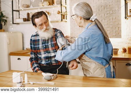 Senior Woman And Man At Home Meassure Blood Pressure