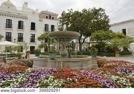 Estepona, Spain - Estepona 1, 2020: Color Flowers Around Fountain In Square Of Estepona, A Village L