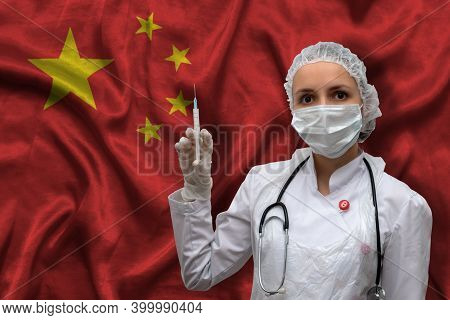 Young Woman Doctor In Medical Uniform On The Background Of The National Flag Of China Is Holding A S