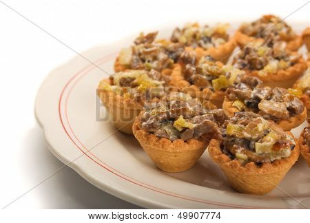 Mini tartlets  with mushrooms, cheese and vegetables on white plate