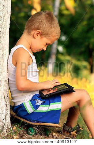 Boy Child Playing With Tablet Pc Outdoor With Forest On Background Computer Game Dependence Concept