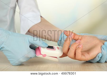 Doctor measuring pulse rate and oxygen levels, on bright background