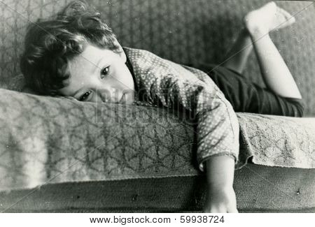 KURSK, USSR - CIRCA 1976:  An antique photo shows  portrait of a little boy lying on the sofa.