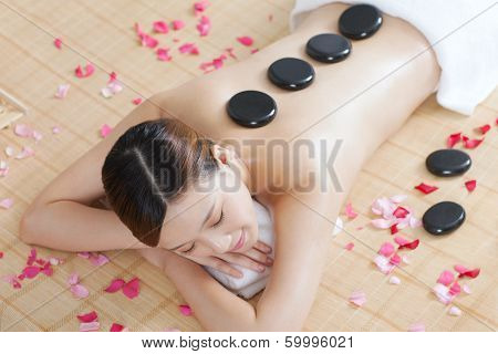 .a Young Lady Enjoying Stone Massage At Spa.