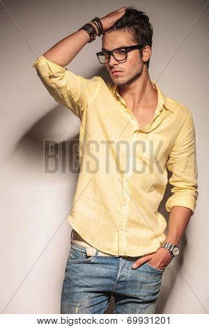 relaxed casual fashion man passing his hand through his hair in studio, looking away from the camera