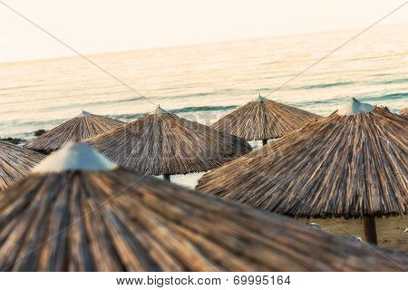 Sandy Beach With Straw Umbrellas And Sunbeds