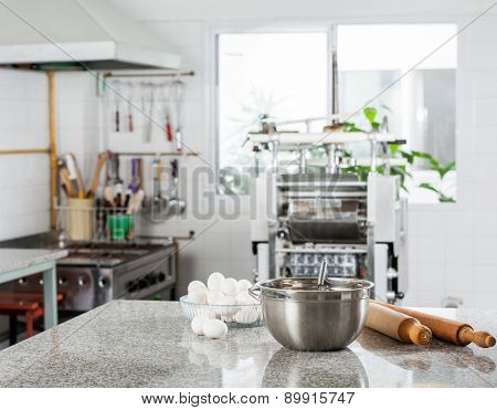 Mixing bowl with eggs and rolling pin on counter in commercial kitchen