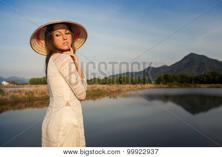 Portrait Of Girl In Vietnamese Hat Against Country Lakes