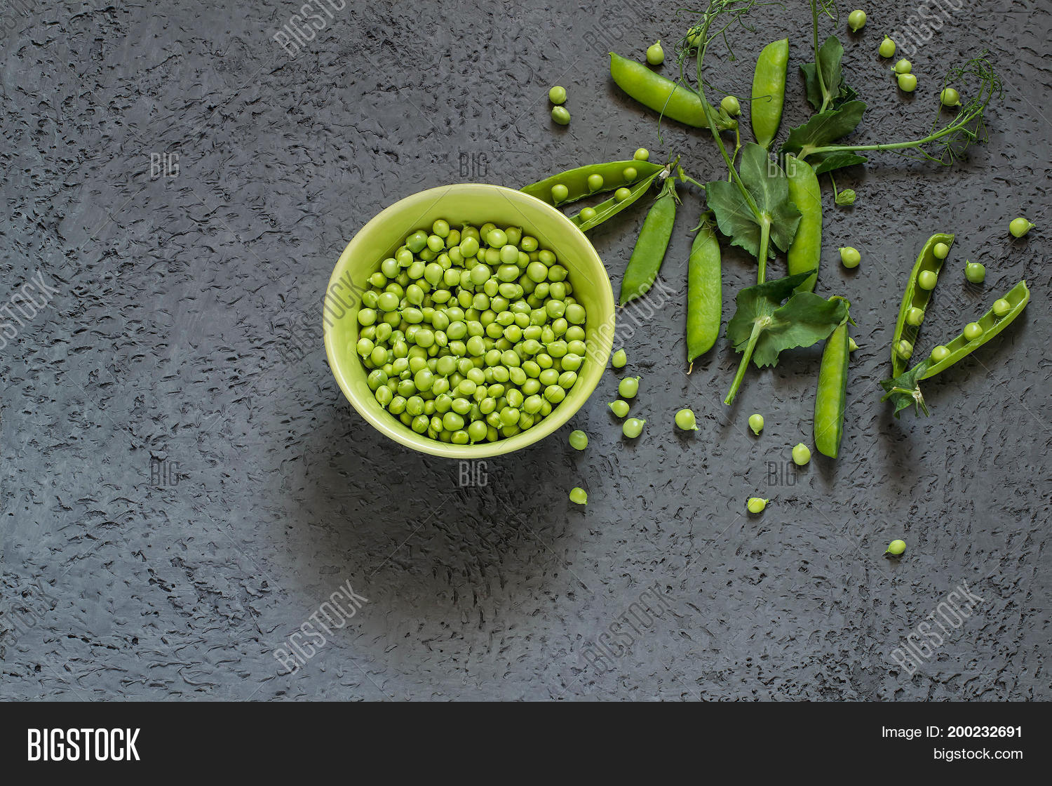 branch of fresh green peas with pods and leaves near bowl with