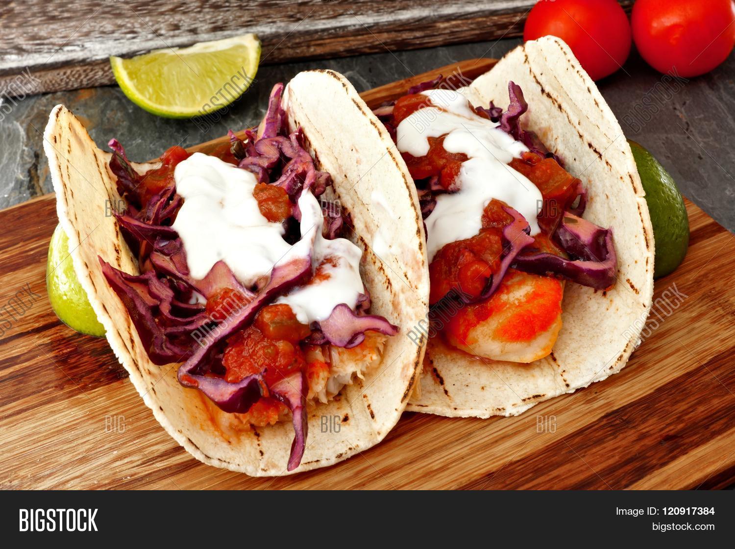 two spicy fish tacos with red cabbage lime slaw salsa and sour