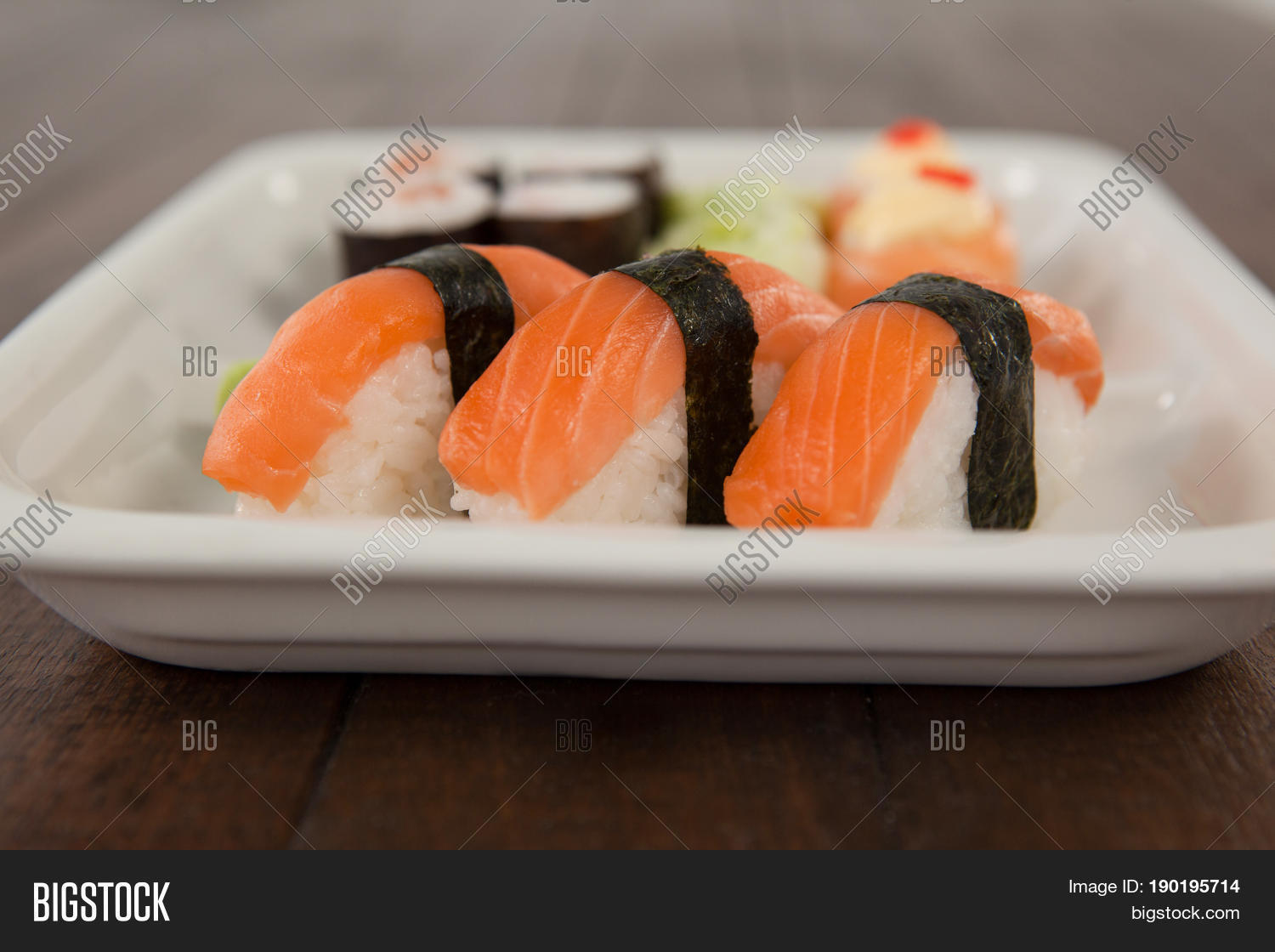 three nigiri sushi served in white plate on wooden table