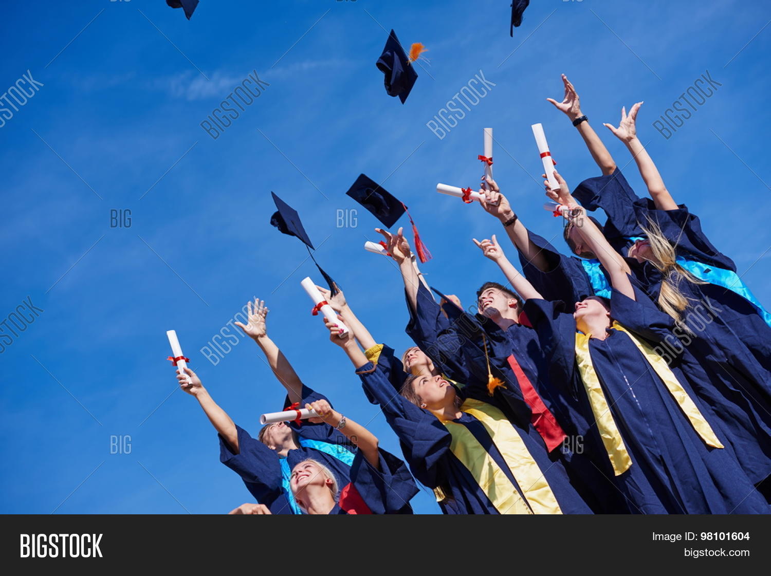high school students graduates tossing up hats over blue sky.
