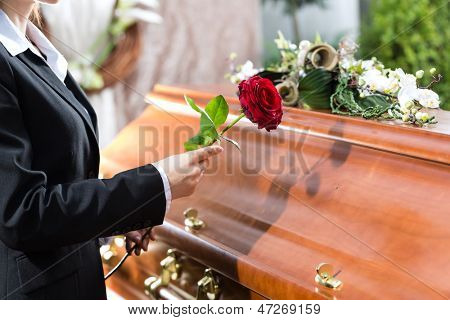 悲伤的葬礼,红玫瑰站在棺材或棺材上的女人