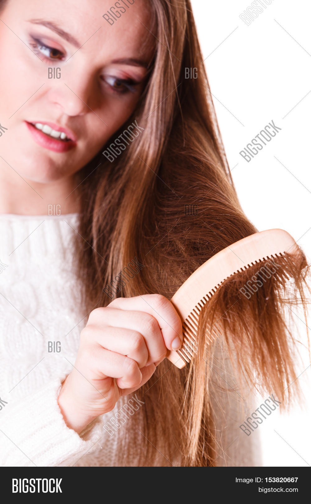 dissatisfied woman combing with brush and pulls at her long hair
