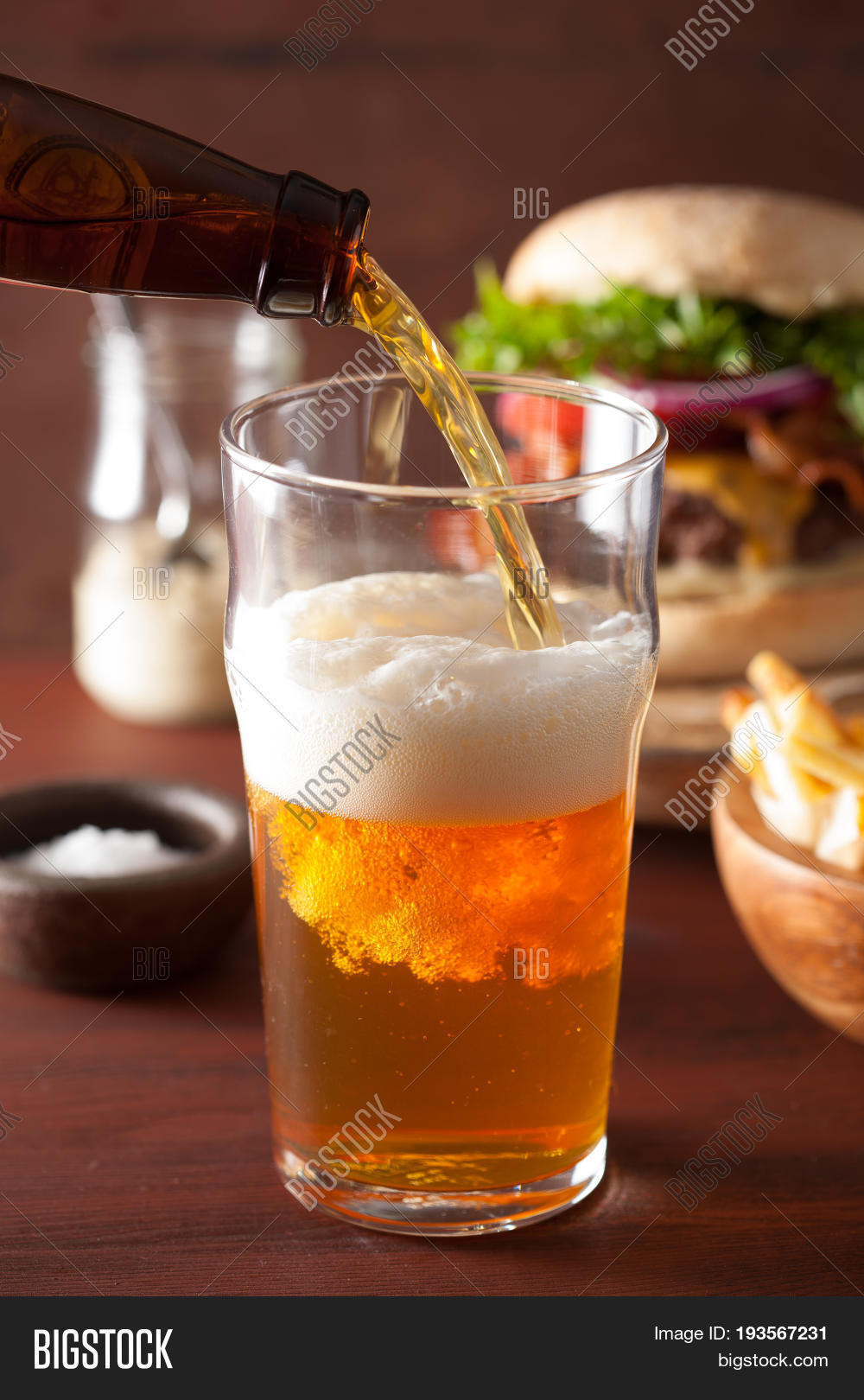 pouring india pale ale beer into pint glass and fast food