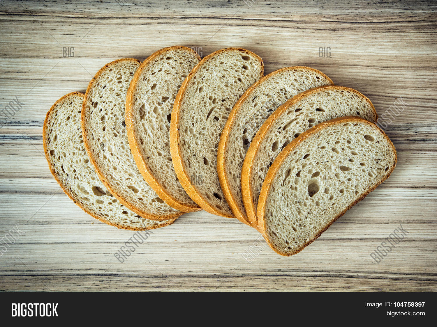 sliced wheaten bread on the wooden background. food theme.