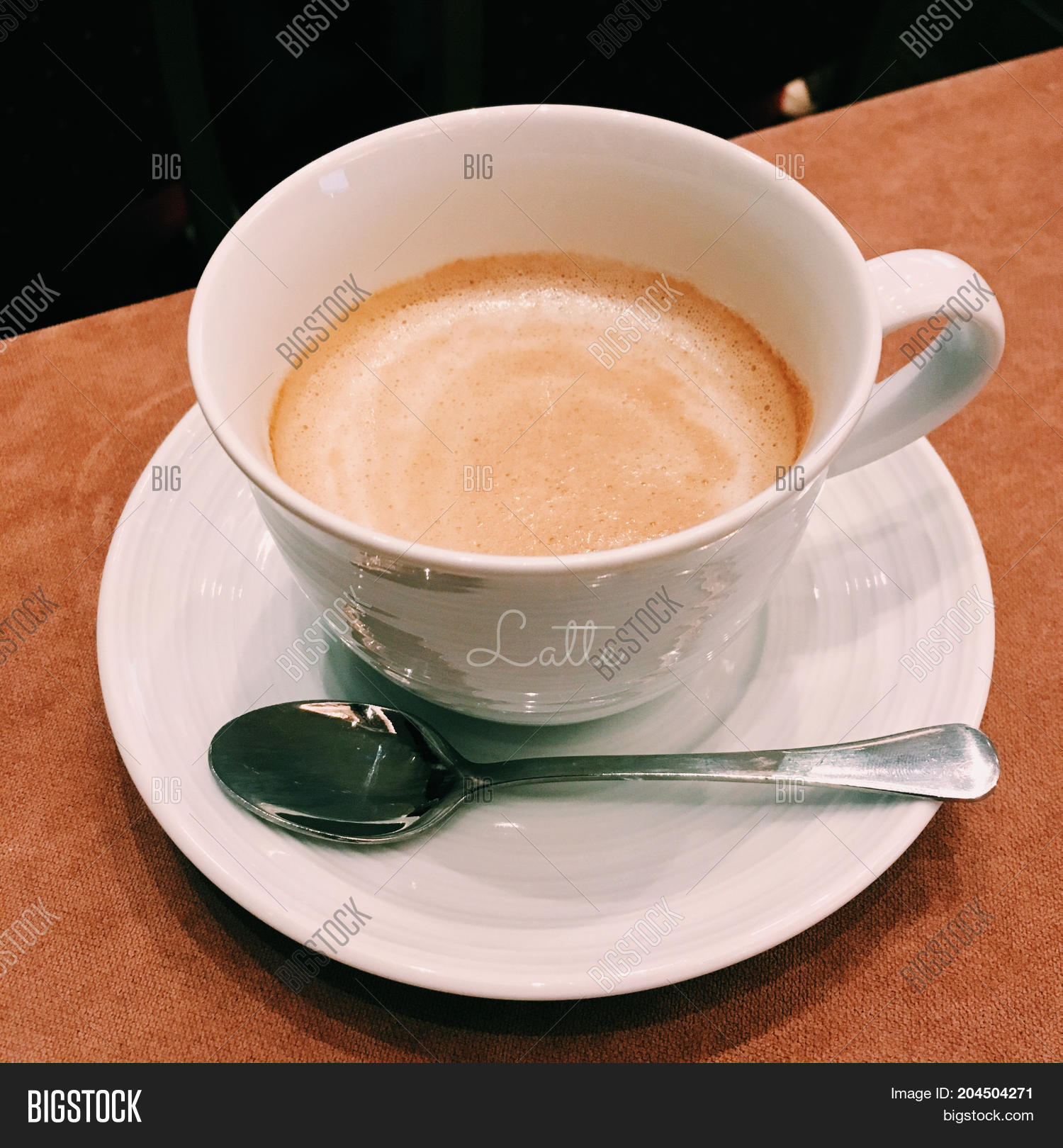 coffee with froth milk in white cup serve on white plate & metal