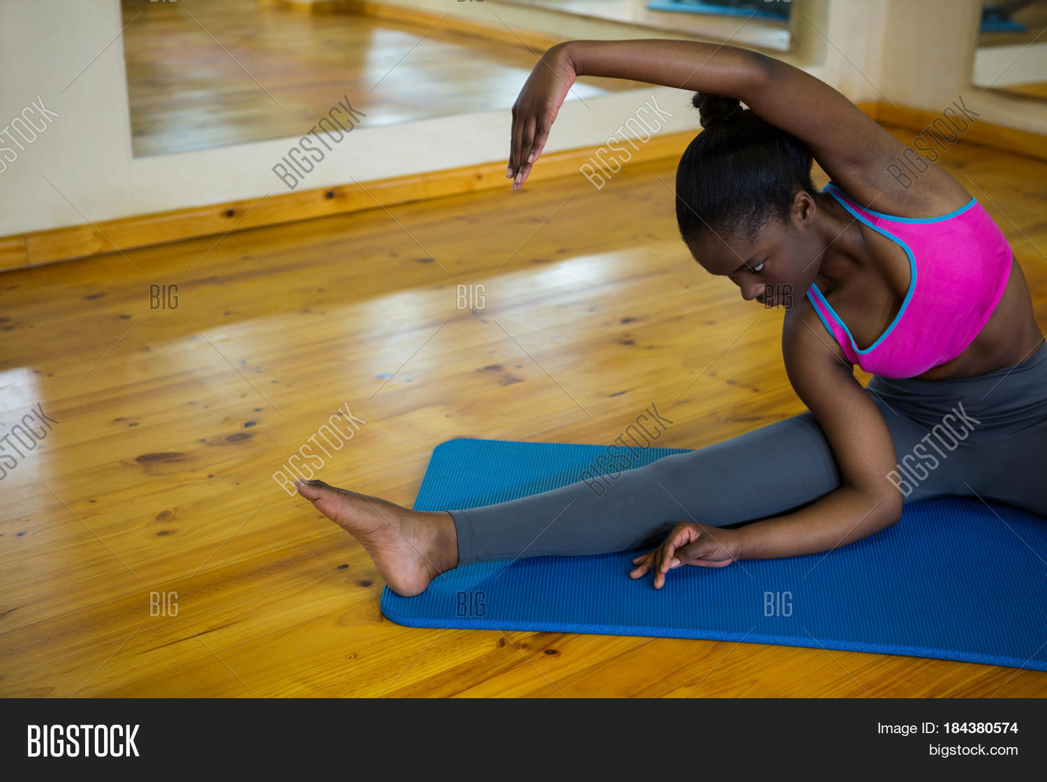 fit woman doing stretching exercise on mat in fitness studio