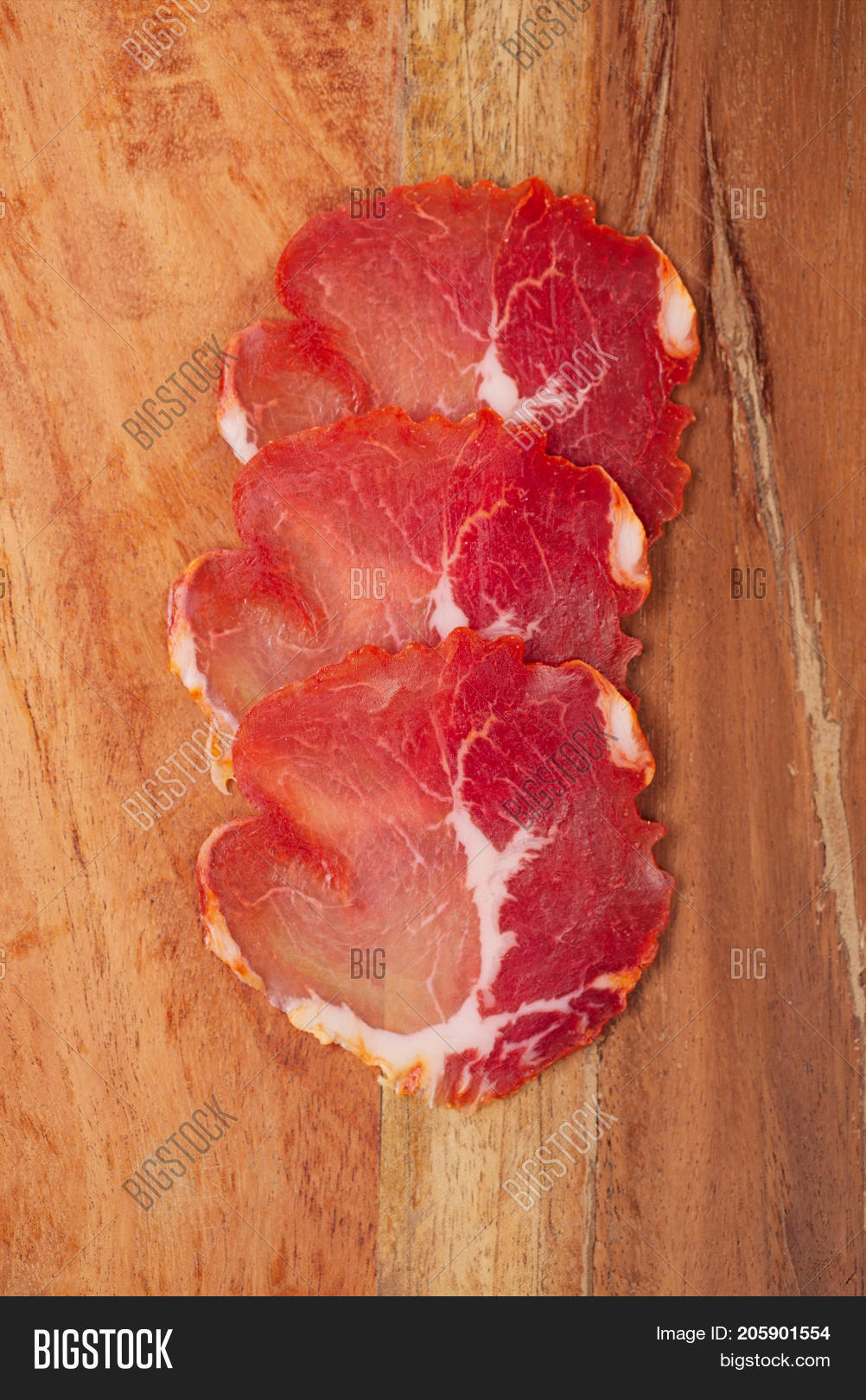 cured meat sandwich with seeded bread on old wooden table