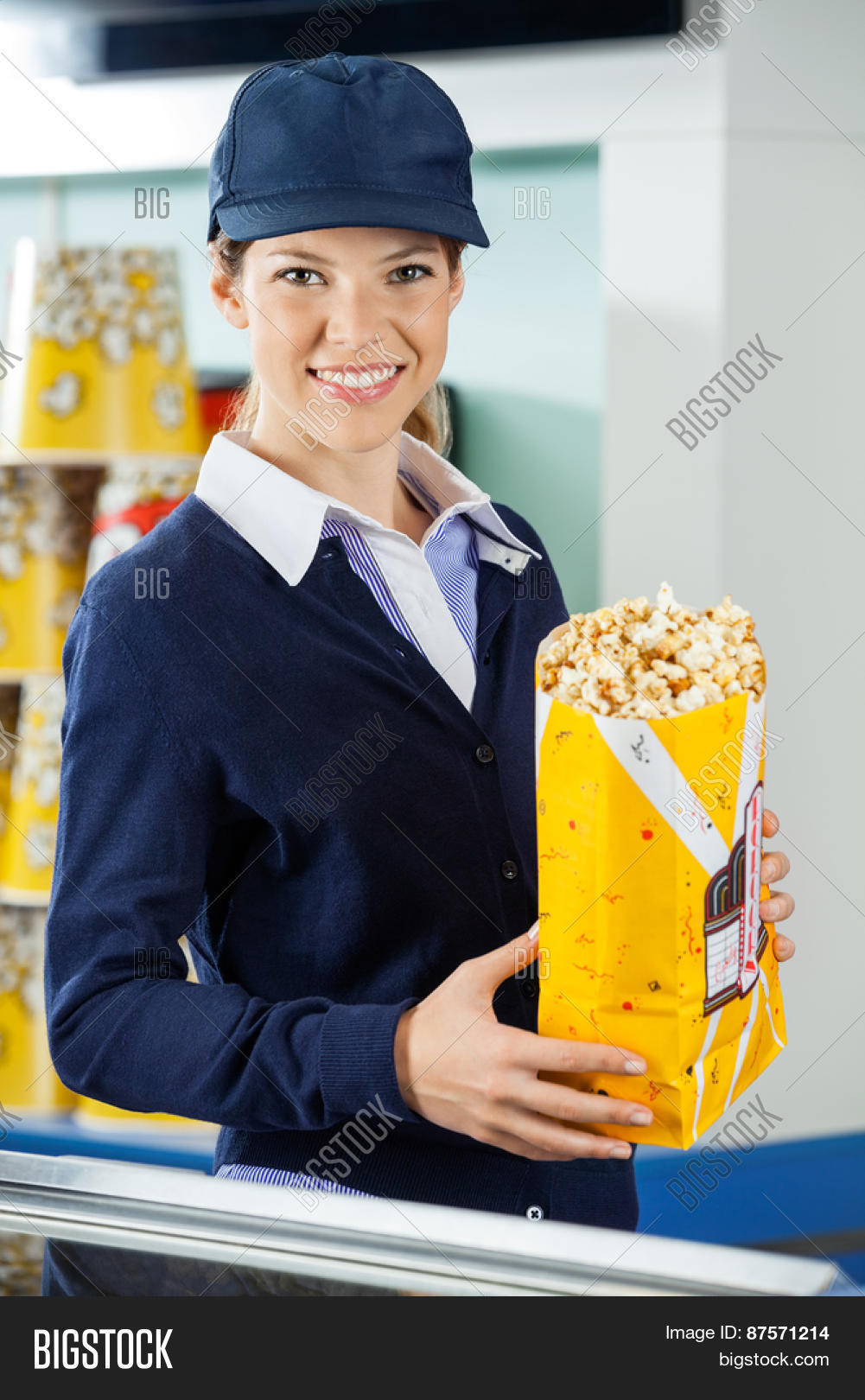 portrait of beautiful female worker holding popcorn paperbag at