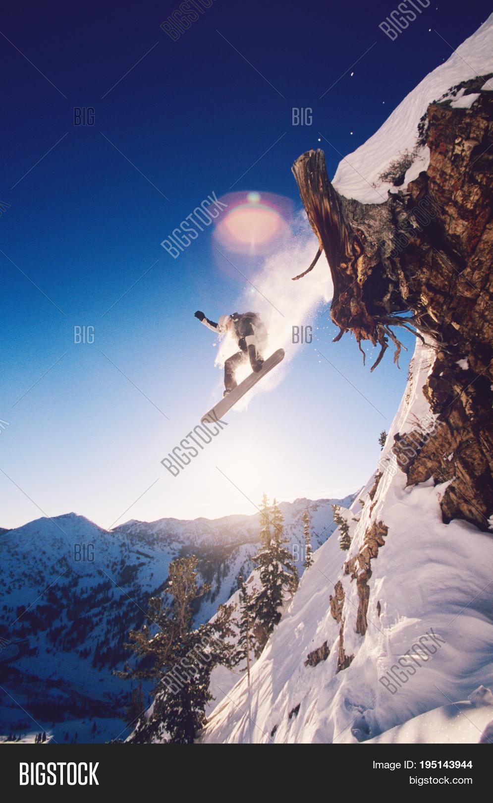 low angle view of snowboarder jumping from mountain ledge