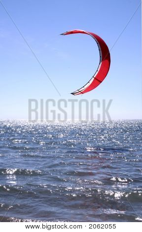 Red Kite Surfer Sail against a blue sky hanging just above the surf. : Bigstock