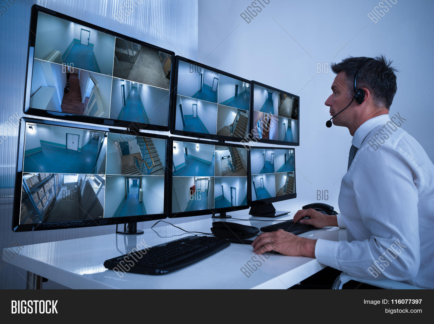 rear view of security system operator looking at cctv footage at