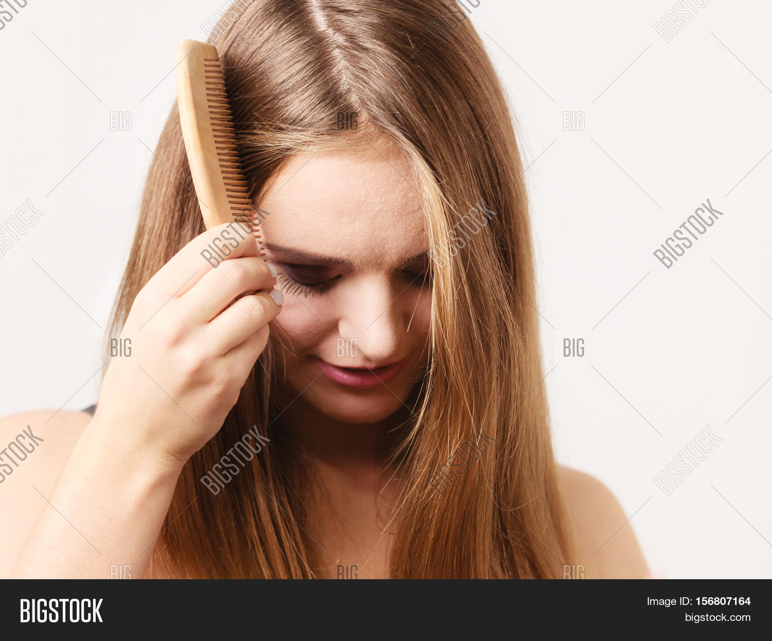 woman refreshing her hairstyle combing long hair with wooden