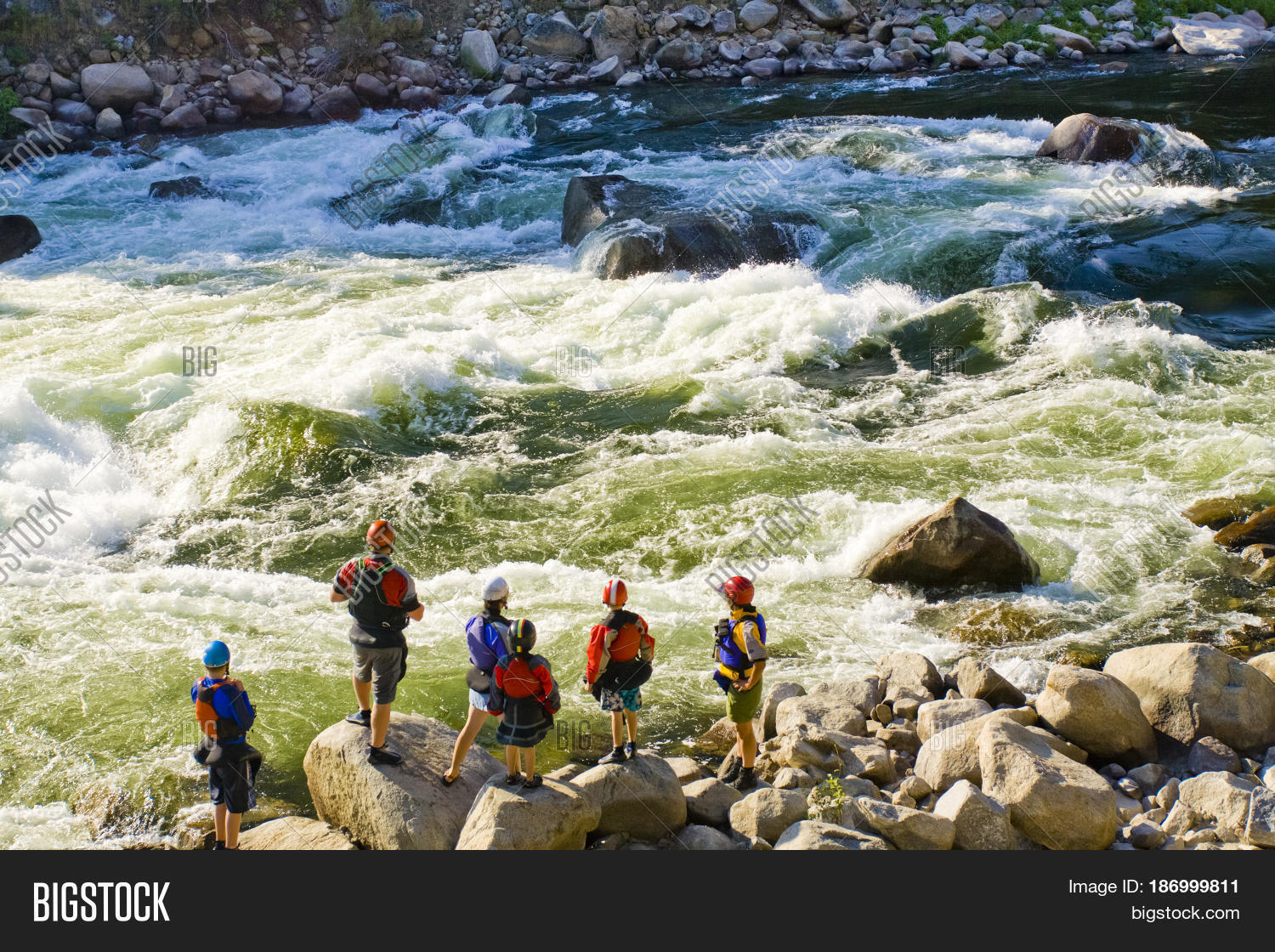 caucasian family standing near rapids in river