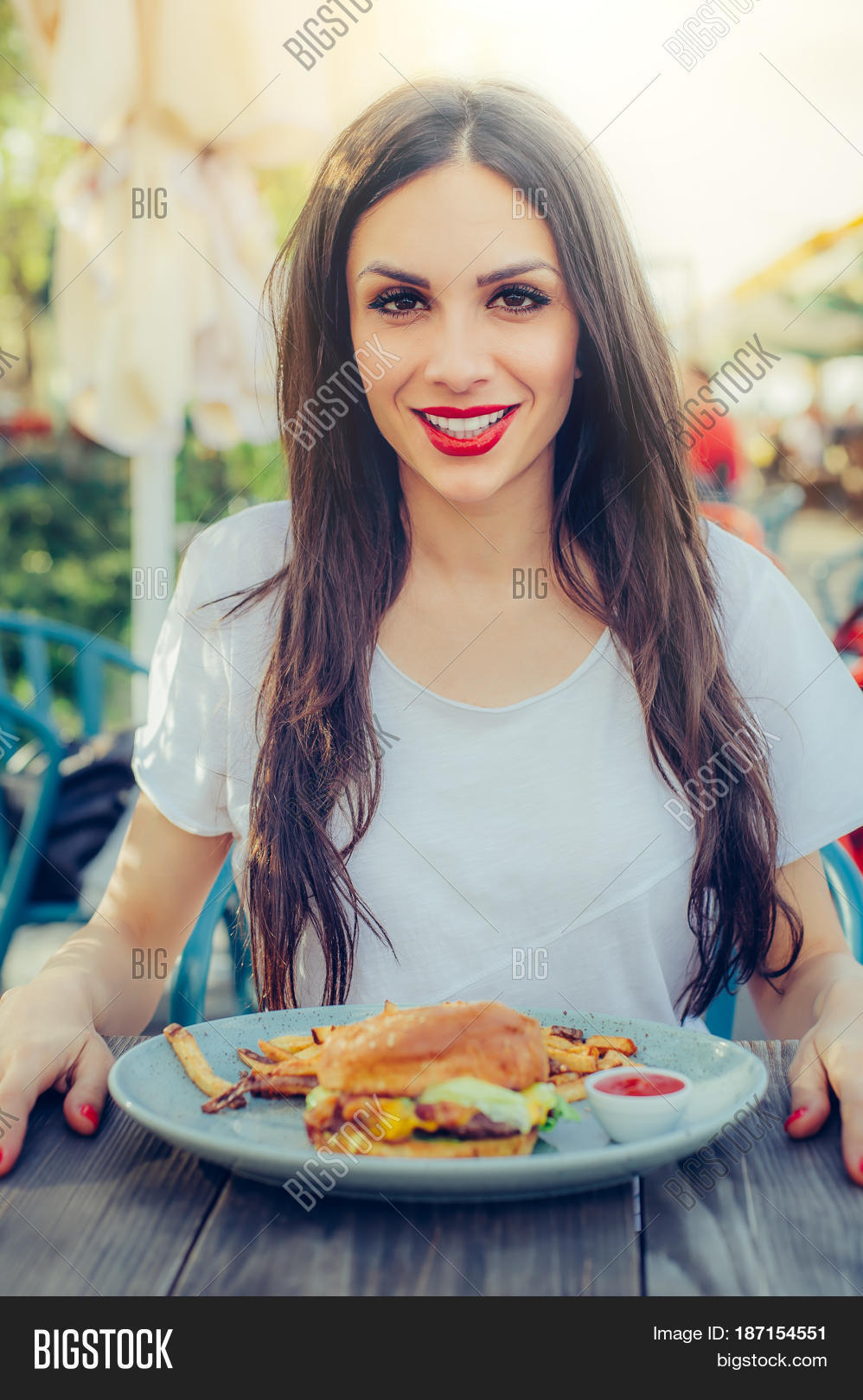 portrait of a young happy woman eating tasty fast food burger