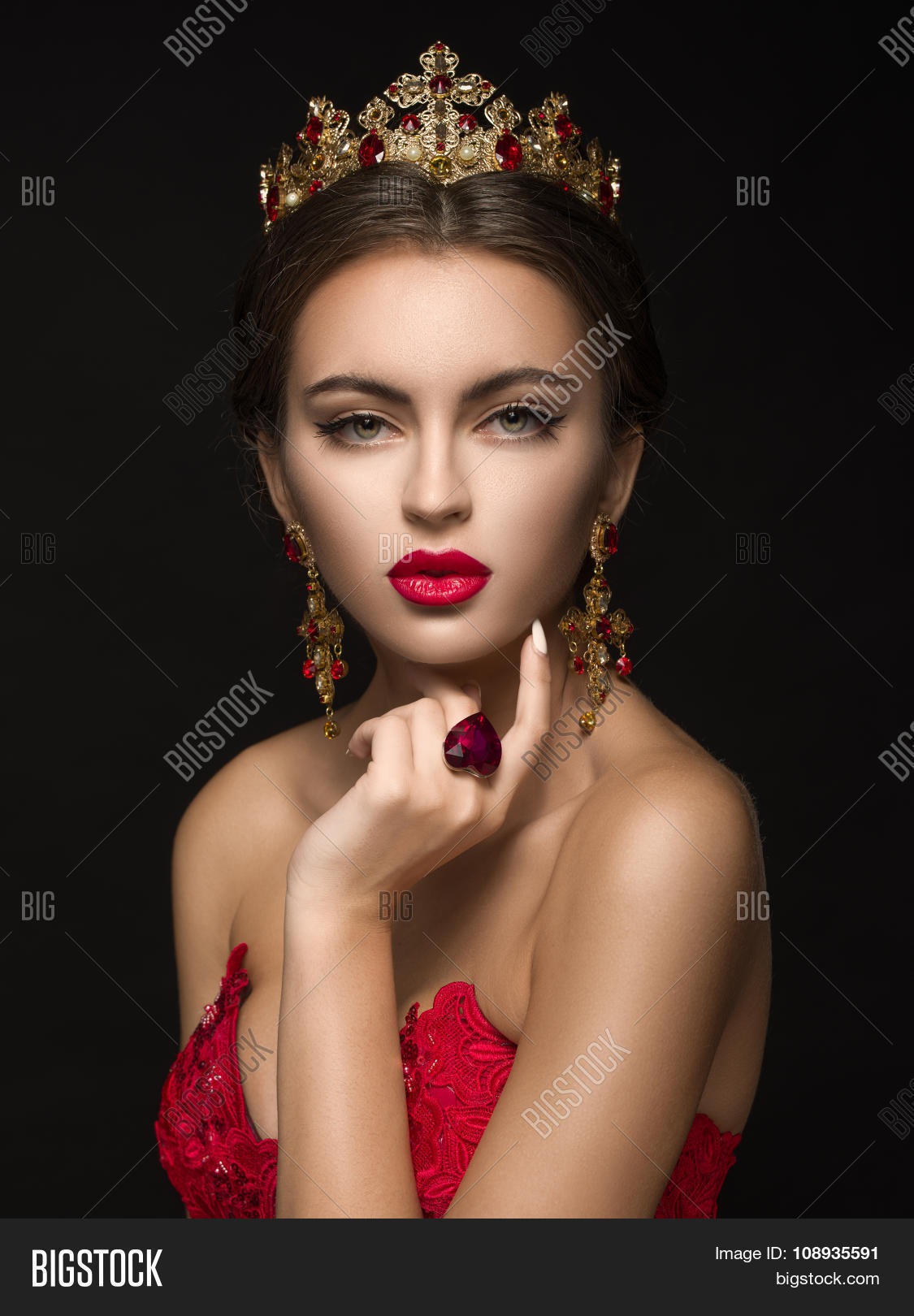 beautiful girl in a golden crown and earrings on a dark back