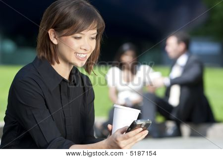 Stock photo : Beautiful Young Asian Woman Texting And Drinking Coffee