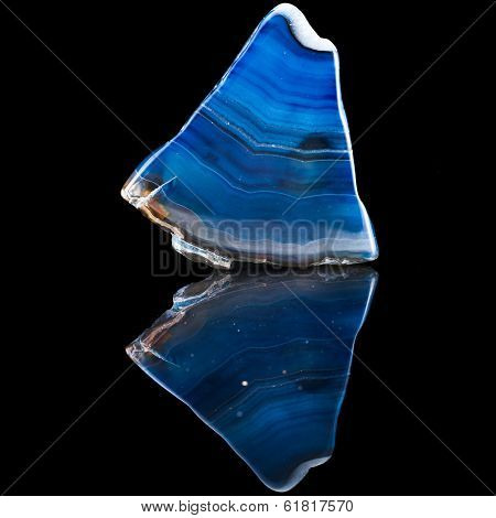 a slice of blue agate crystal with reflection on black surface