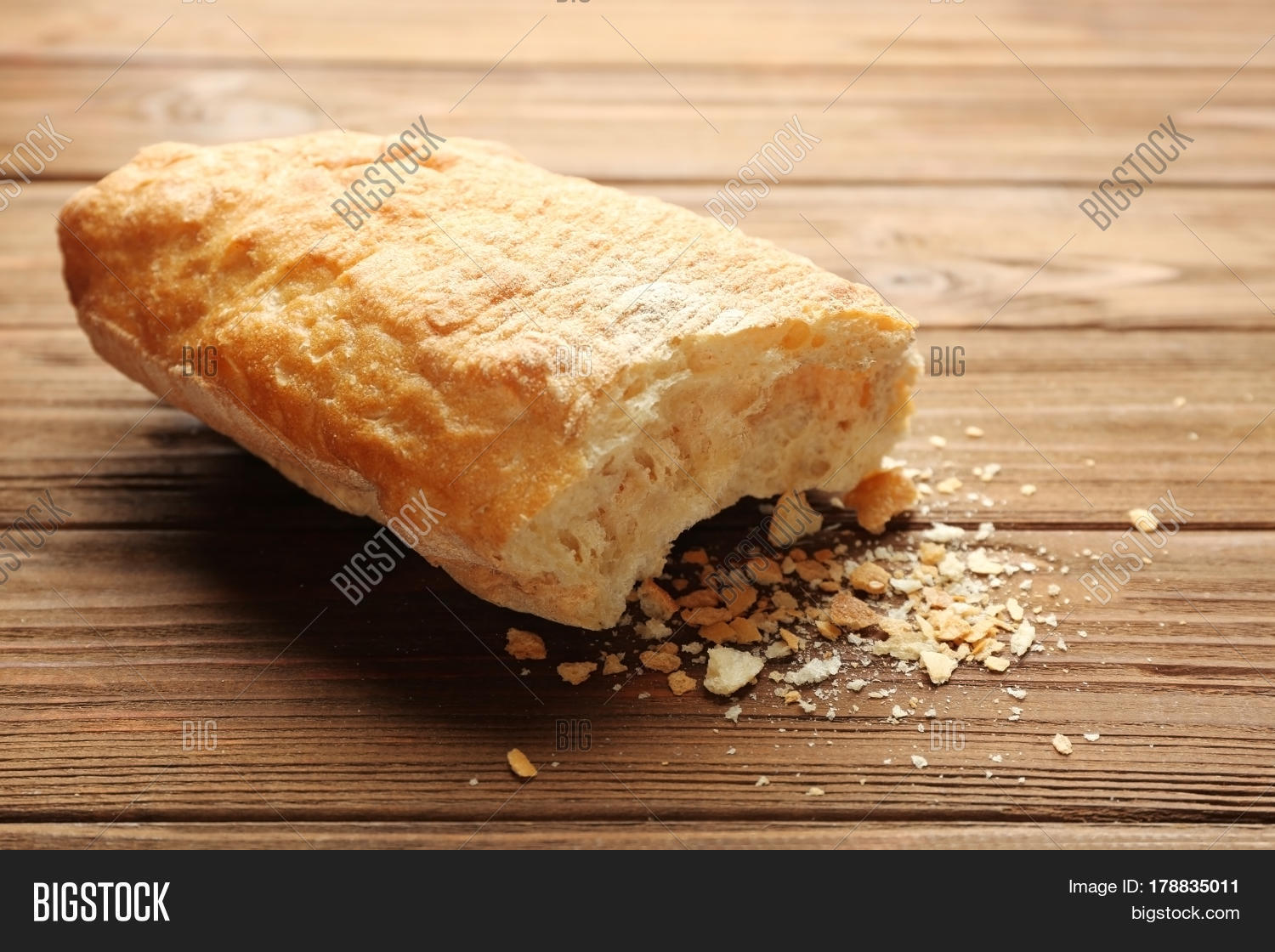 broken wheaten loaf on wooden background