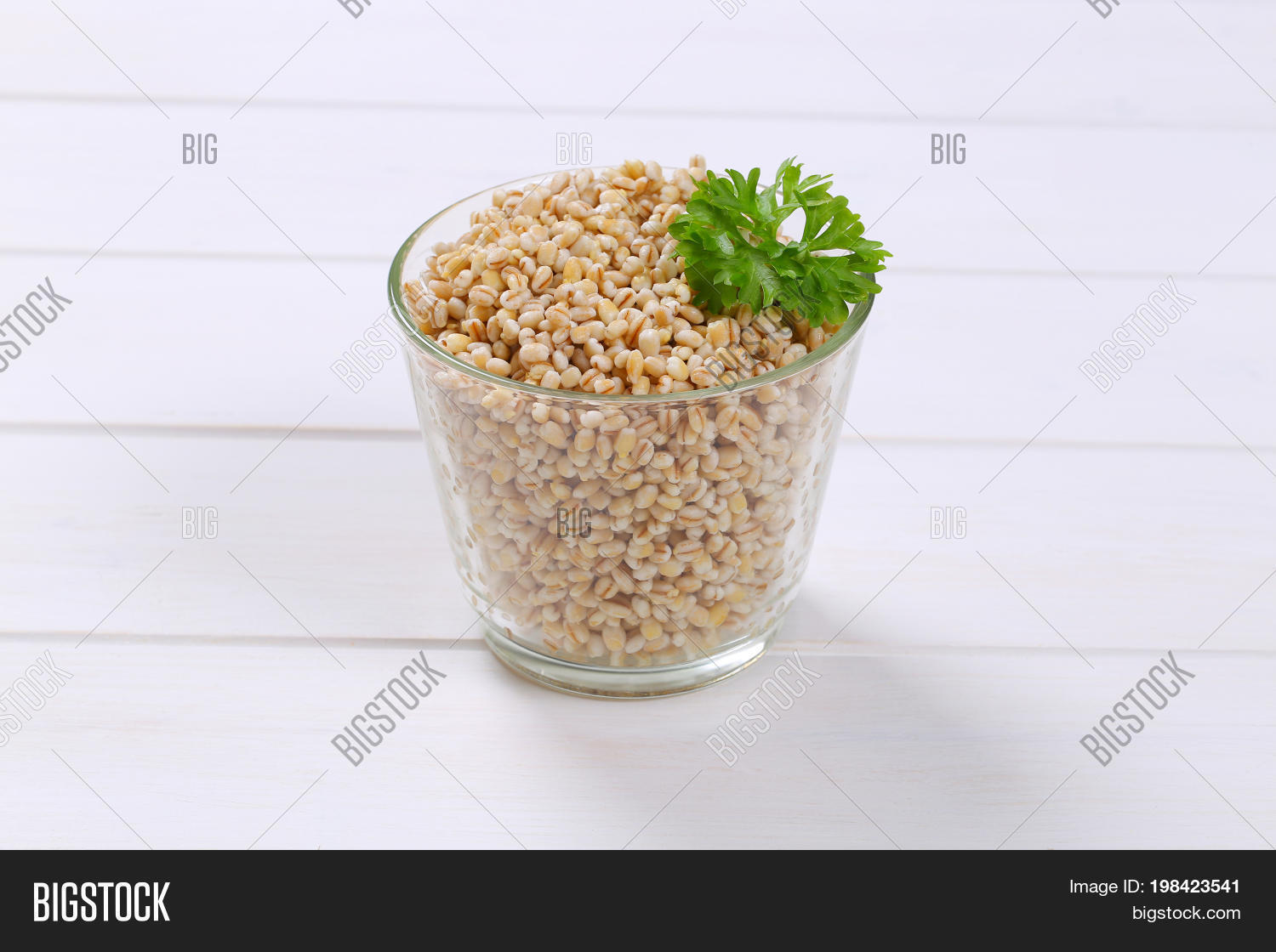 glass of cooked pearl barley on white wooden background