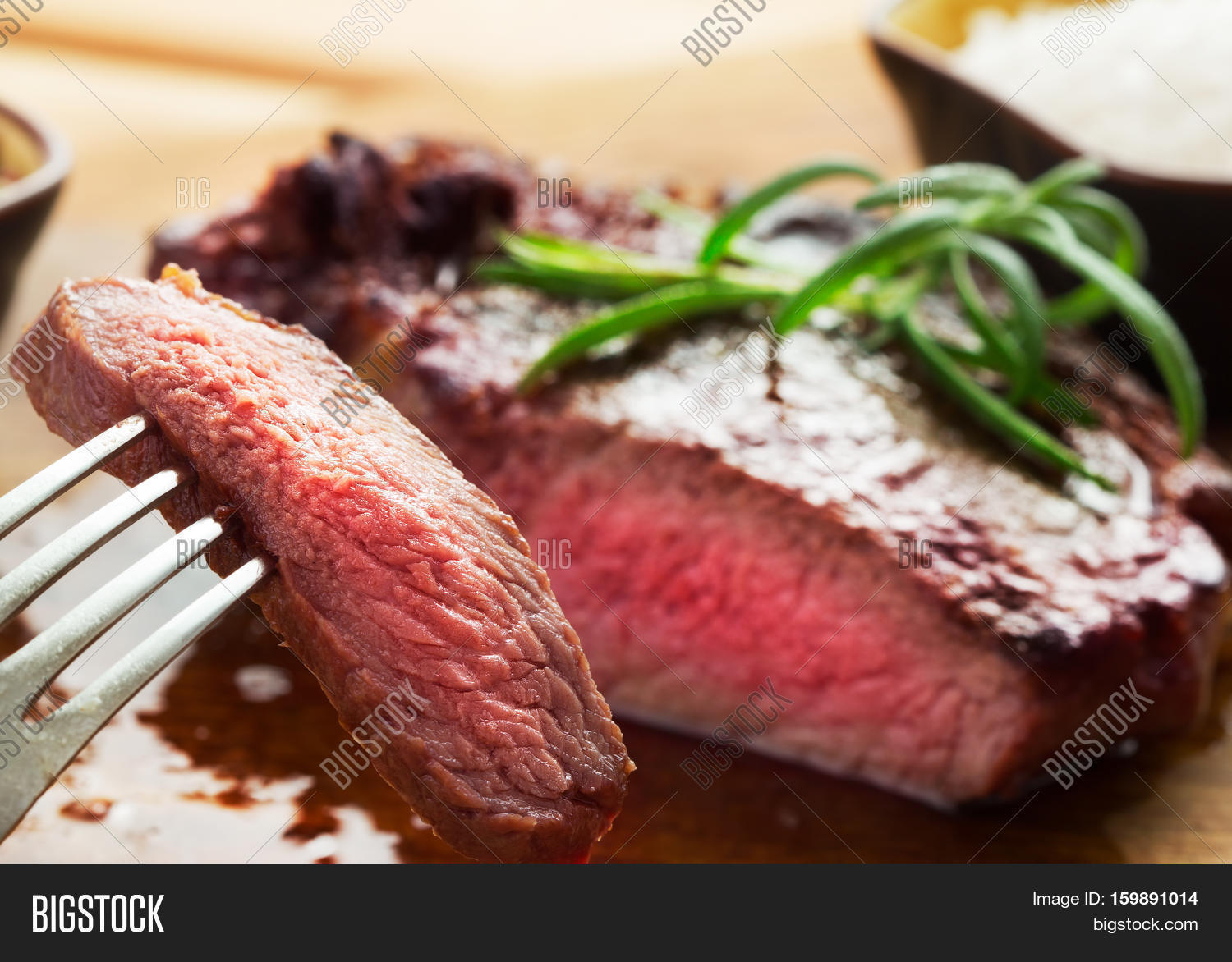 medium roast rib-eye steak on wooden plate with pepper and salt