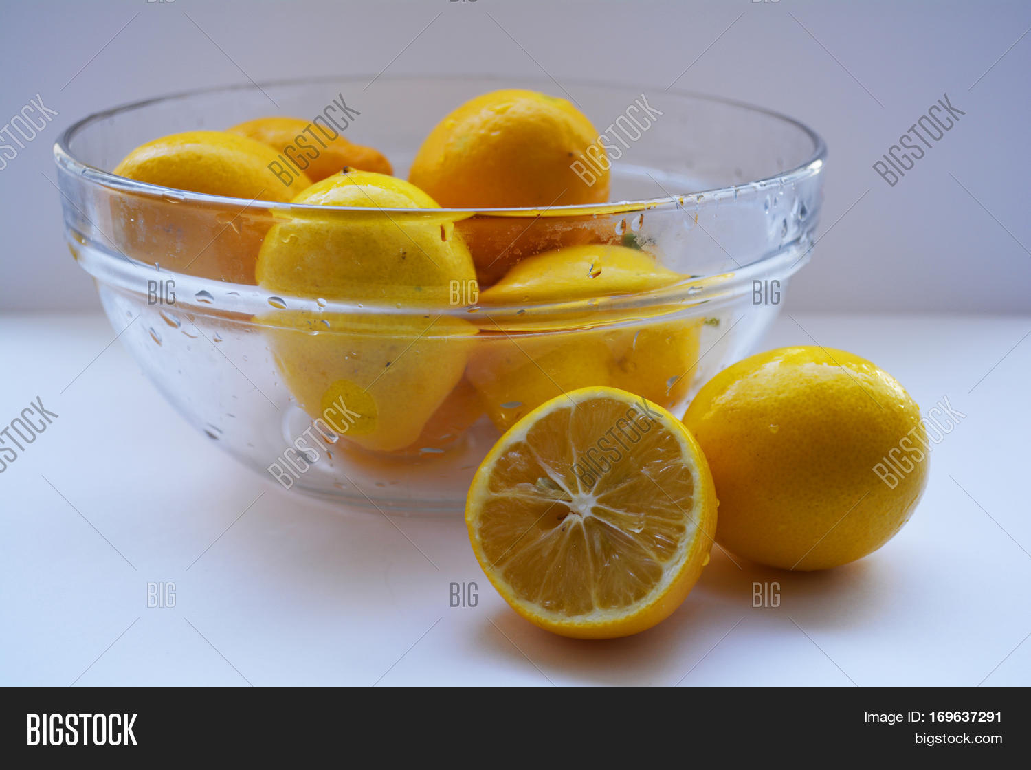 bowl of lemons on a white background and a lemon wedge